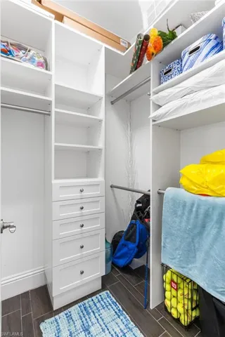 Walk in closet with dark hardwood / wood-style floors