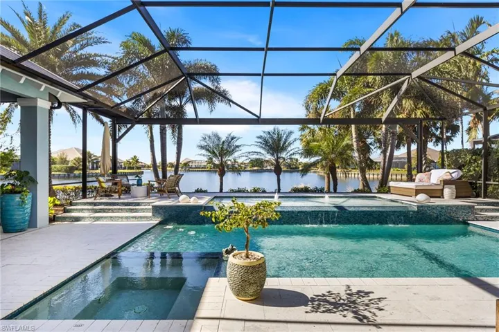 View of pool with a lanai, pool water feature, an in ground hot tub, a water view, and a patio