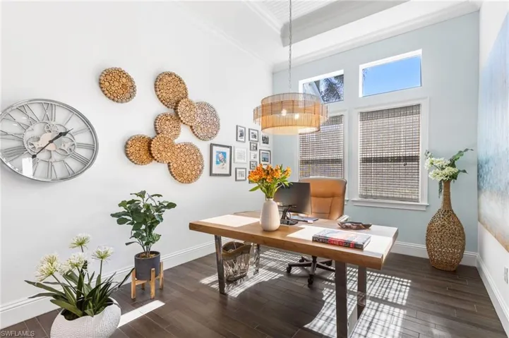Office space featuring a high ceiling, dark hardwood / wood-style floors, and ornamental molding