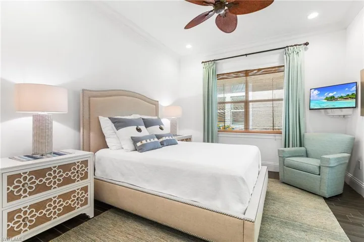 Bedroom with ceiling fan, ornamental molding, and dark wood-type flooring