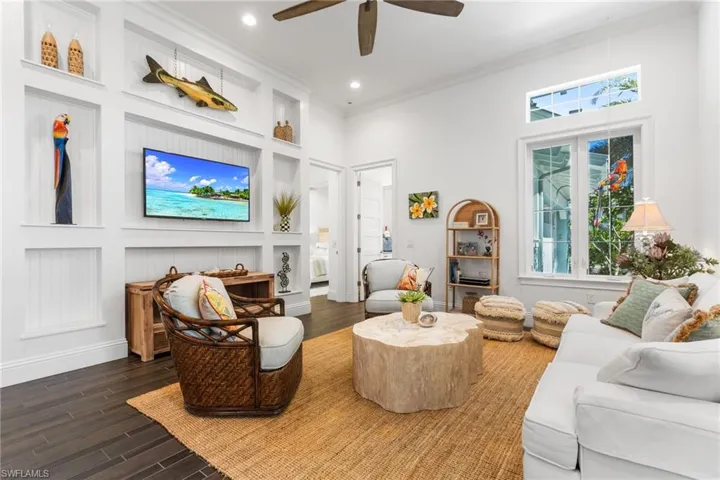 Living room featuring dark hardwood / wood-style floors, ceiling fan, crown molding, and a high ceiling