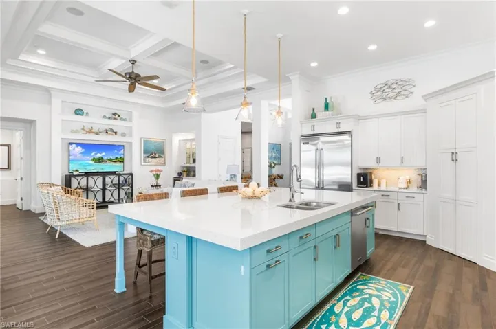 Kitchen featuring white cabinets, sink, hanging light fixtures, an island with sink, and stainless steel appliances