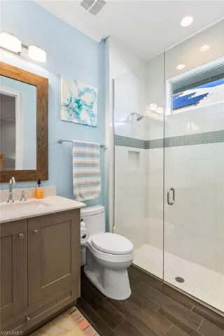 Bathroom featuring vanity, toilet, and a shower with door