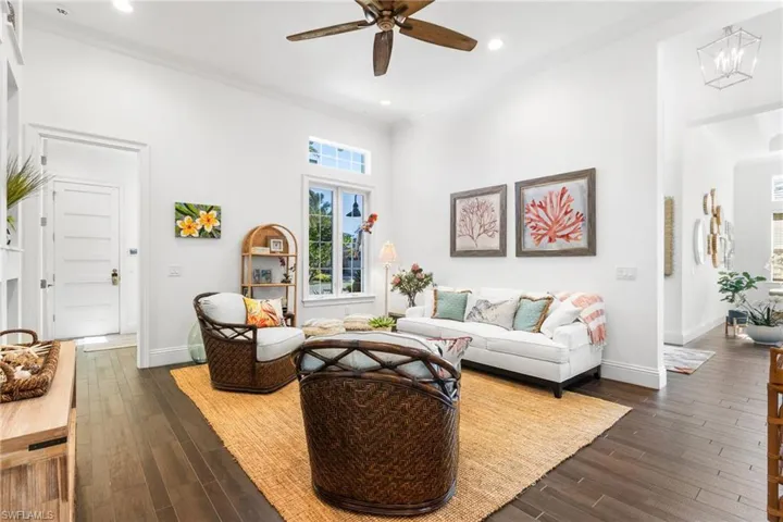 Living room with dark hardwood / wood-style floors, ornamental molding, and ceiling fan with notable chandelier