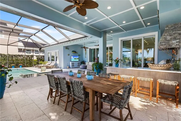 View of patio / terrace with exterior bar, a fenced in pool, ceiling fan, and a lanai