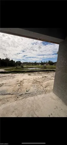 Concrete patio overlooking a landscape featuring a natural pond, grassy terrain, and expansive horizon