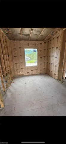 Unfinished interior space featuring exposed wood framing, installed wall insulation, a concrete subfloor, and a single-pane window