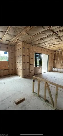 Structural framing with installed batt insulation, concrete slab flooring, and integrated sliding glass door