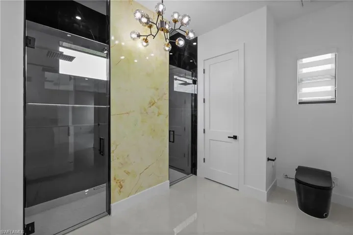 Full bath with a chandelier and a shower stall