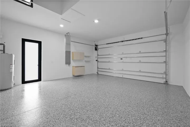 Garage featuring electric water heater, electric panel, and recessed lighting