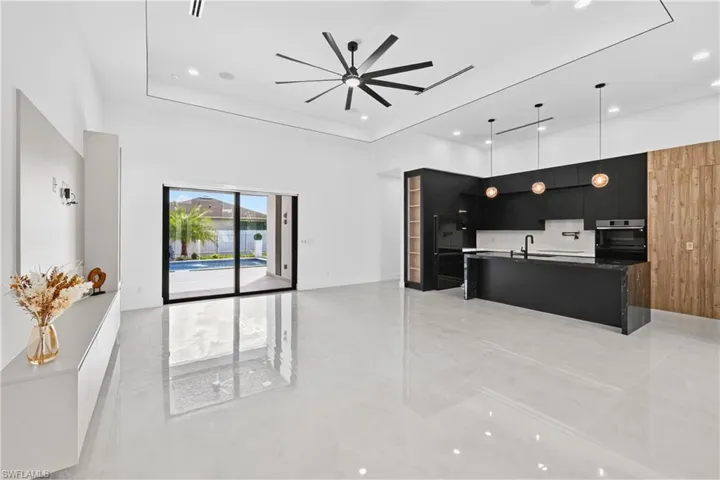 Kitchen with dark cabinets, modern cabinets, a spacious island, open floor plan, and a ceiling fan