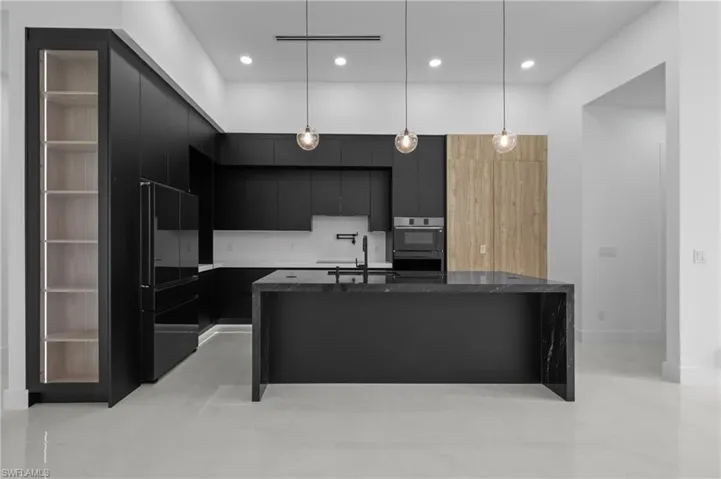 Kitchen featuring dark cabinets, modern cabinets, decorative light fixtures, a kitchen island with sink, and recessed lighting