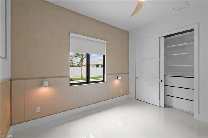 Unfurnished bedroom featuring a wainscoted wall, ceiling fan, and a closet