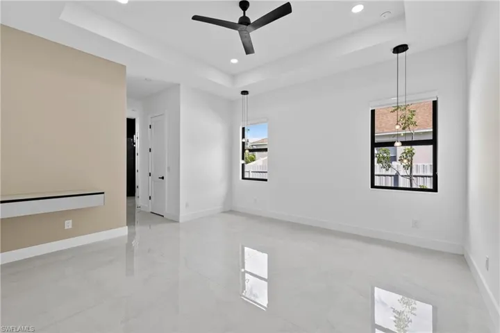 Unfurnished room featuring a raised ceiling, a ceiling fan, and recessed lighting
