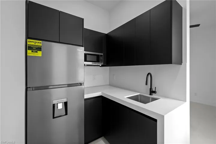 Kitchen featuring dark cabinetry, appliances with stainless steel finishes, modern cabinets, and light stone countertops