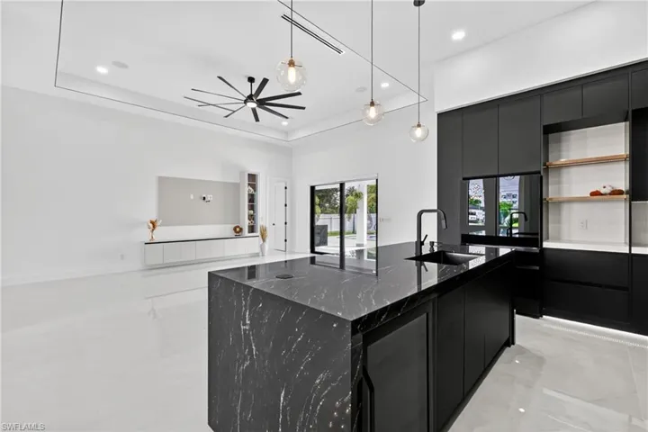 Kitchen with dark cabinets, hanging light fixtures, modern cabinets, open floor plan, and a kitchen island with sink