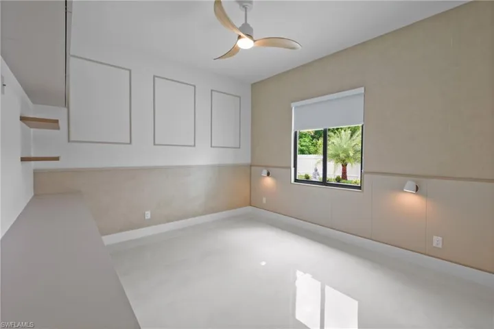 Unfurnished room featuring a ceiling fan and wainscoting