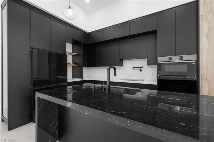 Kitchen featuring modern cabinets, dark cabinets, dark stone countertops, and double wall oven