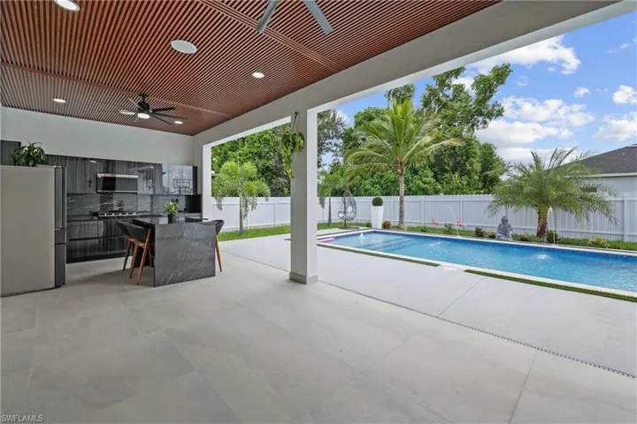 View of swimming pool featuring a patio, a fenced backyard, a ceiling fan, and an outdoor bar