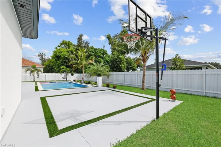 View of sport court with a fenced backyard and a patio
