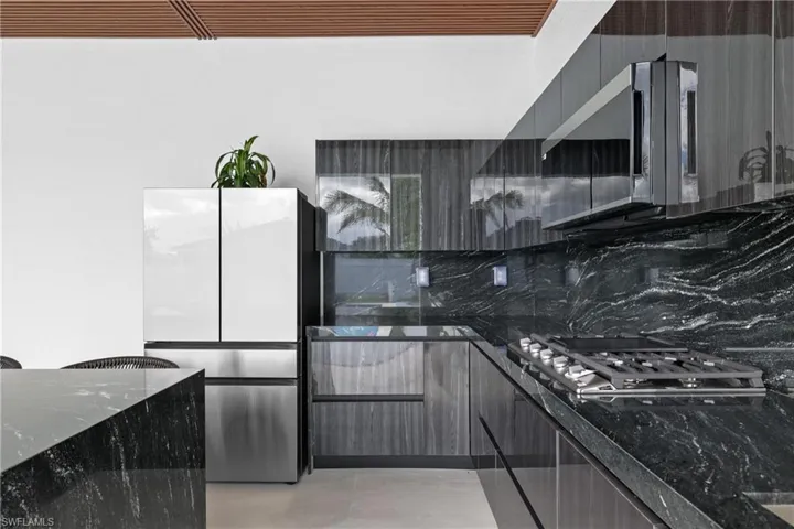 Kitchen with dark stone counters, backsplash, appliances with stainless steel finishes, modern cabinets, and light tile patterned floors