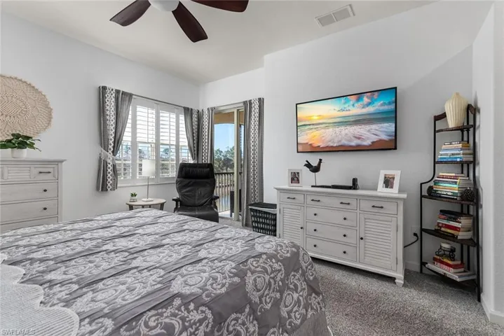 Bedroom featuring access to exterior, dark colored carpet, and ceiling fan