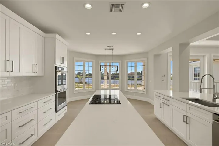 Kitchen with white cabinets, appliances with stainless steel finishes, sink, decorative light fixtures, and backsplash