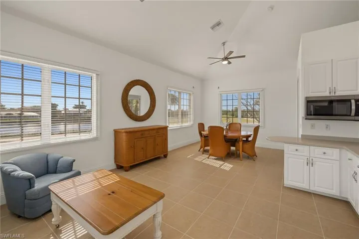 Tiled living room with vaulted ceiling, ceiling fan, and plenty of natural light