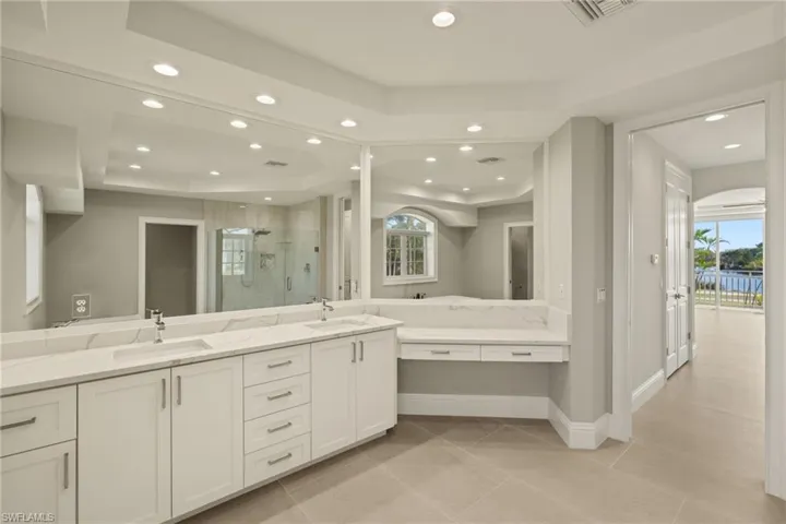 Bathroom with a shower with door, a tray ceiling, a wealth of natural light, and vanity