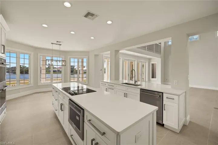 Kitchen featuring stainless steel dishwasher, pendant lighting, black electric stovetop, white cabinetry, and sink