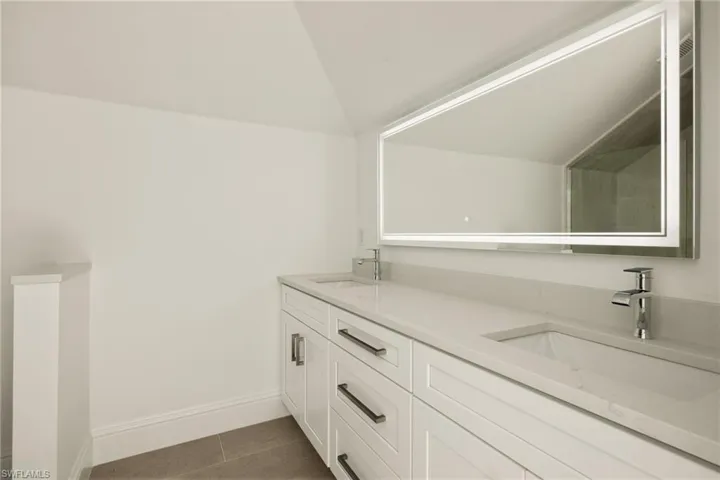 Bathroom with tile patterned floors, lofted ceiling, and vanity