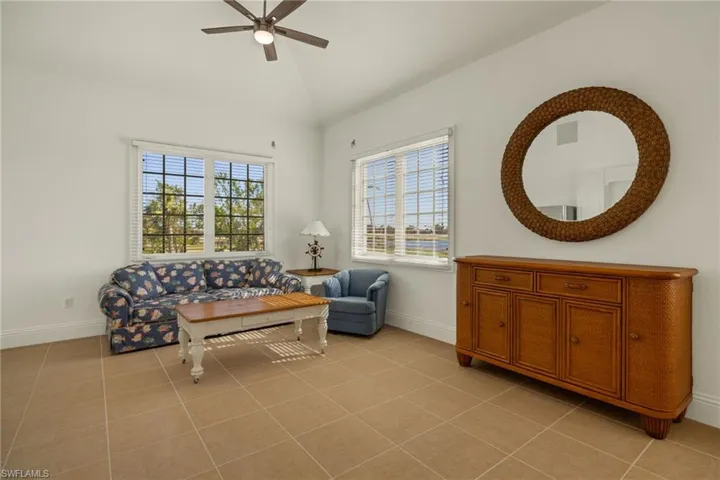 Living area with lofted ceiling, ceiling fan, light tile patterned floors, and a healthy amount of sunlight