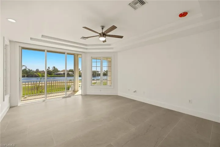 Spare room with ceiling fan, a water view, and a tray ceiling