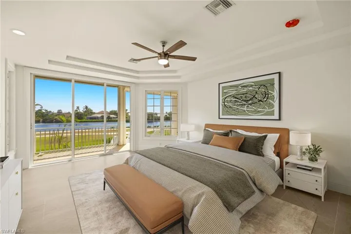 Bedroom with visible vents, access to exterior, a raised ceiling, a water view, and a ceiling fan