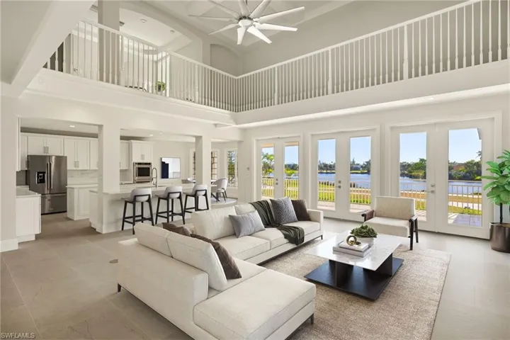 Living room with french doors, a water view, a high ceiling, and a ceiling fan
