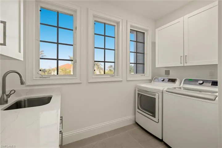 Laundry room featuring washer and dryer, cabinets, light tile patterned flooring, and sink