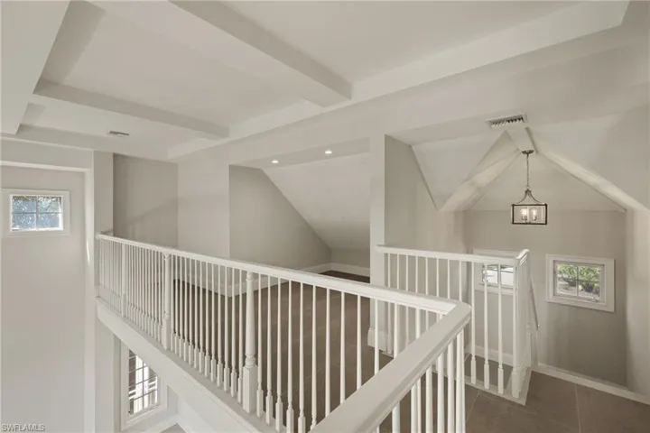 Corridor featuring vaulted ceiling with beams, an inviting chandelier, and a wealth of natural light