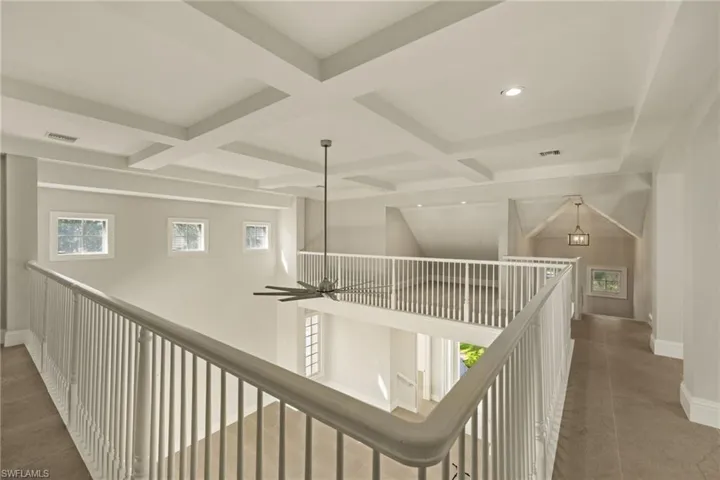 Corridor with beam ceiling, dark tile patterned floors, and coffered ceiling