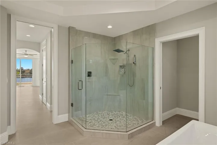 Bathroom featuring walk in shower, tile patterned flooring, ceiling fan, and a water view