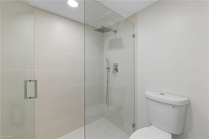 Bathroom featuring a shower with door and toilet