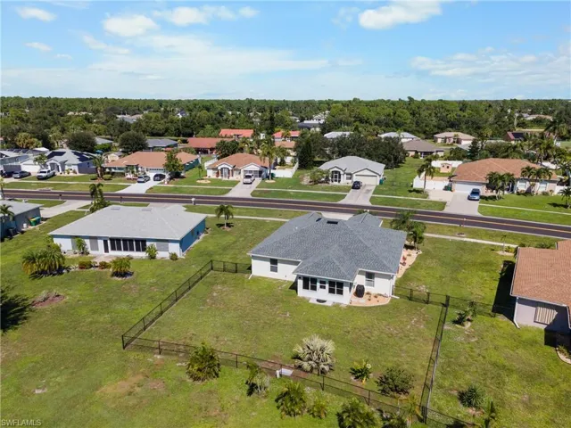 Single-story residence featuring a shingled roof, attached two-car garage, enclosed rear lanai, and a fenced backyard