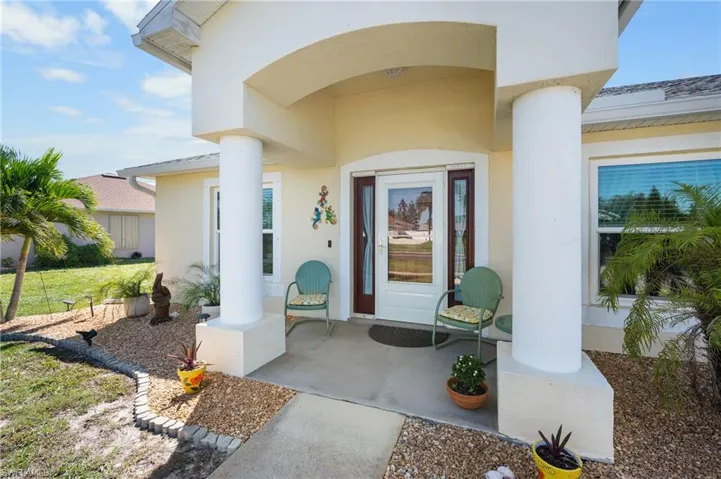 Covered entryway featuring prominent structural columns, concrete porch flooring, and a glass-panel front door with sidelights