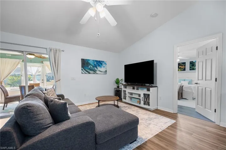 Vaulted ceilings, wood-finish flooring, ceiling fan with integrated lighting, and sliding glass doors