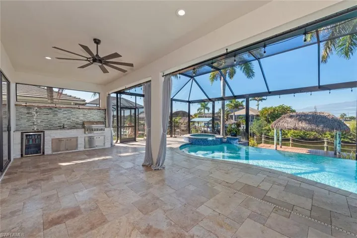 View of swimming pool with a lanai, a patio, a pool with connected hot tub, a sunroom, and area for grilling
