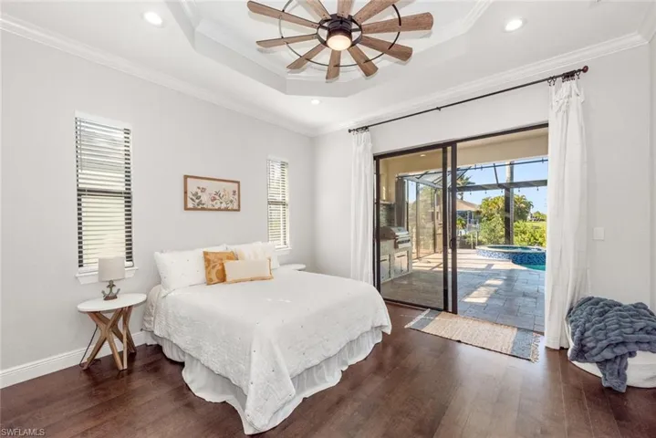 Bedroom with multiple windows, access to outside, ornamental molding, recessed lighting, and a raised ceiling