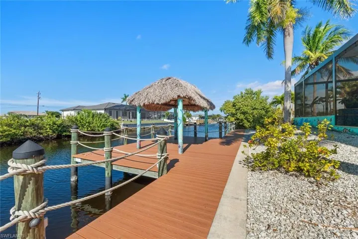 Dock featuring a lanai, boat lift, a water view, and a sunroom