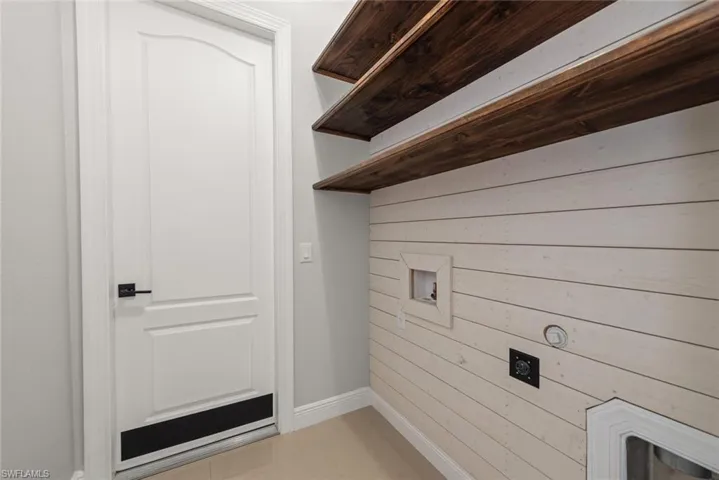 Laundry room with wood walls, hookup for a washing machine, light tile patterned flooring, and hookup for an electric dryer