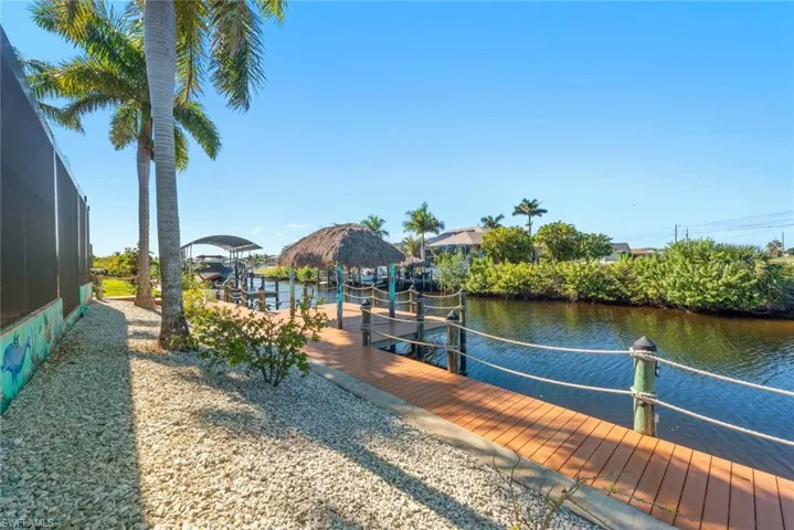 Dock area with boat lift, a water view, and a lanai