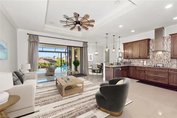 Living area featuring ornamental molding, ceiling fan, light tile patterned flooring, and a raised ceiling