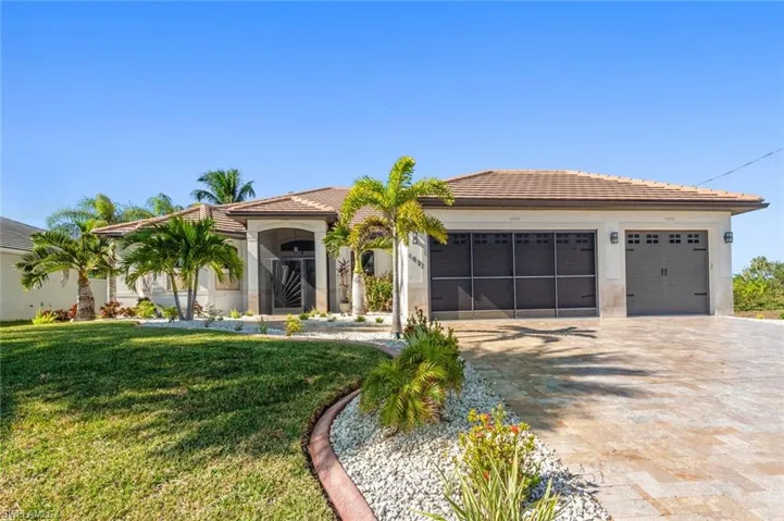 Mediterranean / spanish-style house with a tile roof, decorative driveway, a garage, a front lawn, and stucco siding